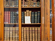 Monolithes par Anaïs Desvignes. Un bloc de plâtre avec la lettre O au centre sur un étagère de bibliothèque parmis les ouvrages. L'épaisseur du bloc dépend du nombre de fois où l'artiste a trouvé la lettre O dans un ouvrage en particulier